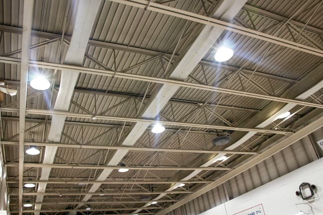 The ceiling of an industrial facility showing round LED high bay lights projecting bright illumination