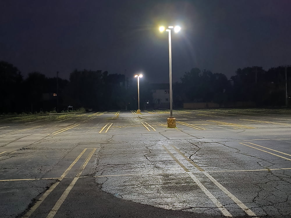 Example of a parking lot lighting project that was improved from metal halides to LEDs the fixture is mounted on a tall parking pole and illuminating the entire lot