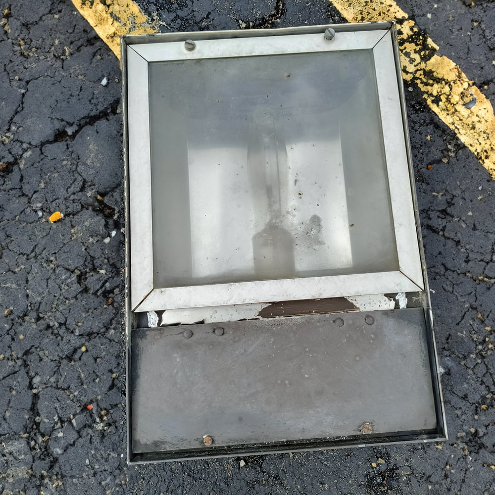 Old metal halide flood light fixture the size of a shoebox that was taken off a parking lot pole