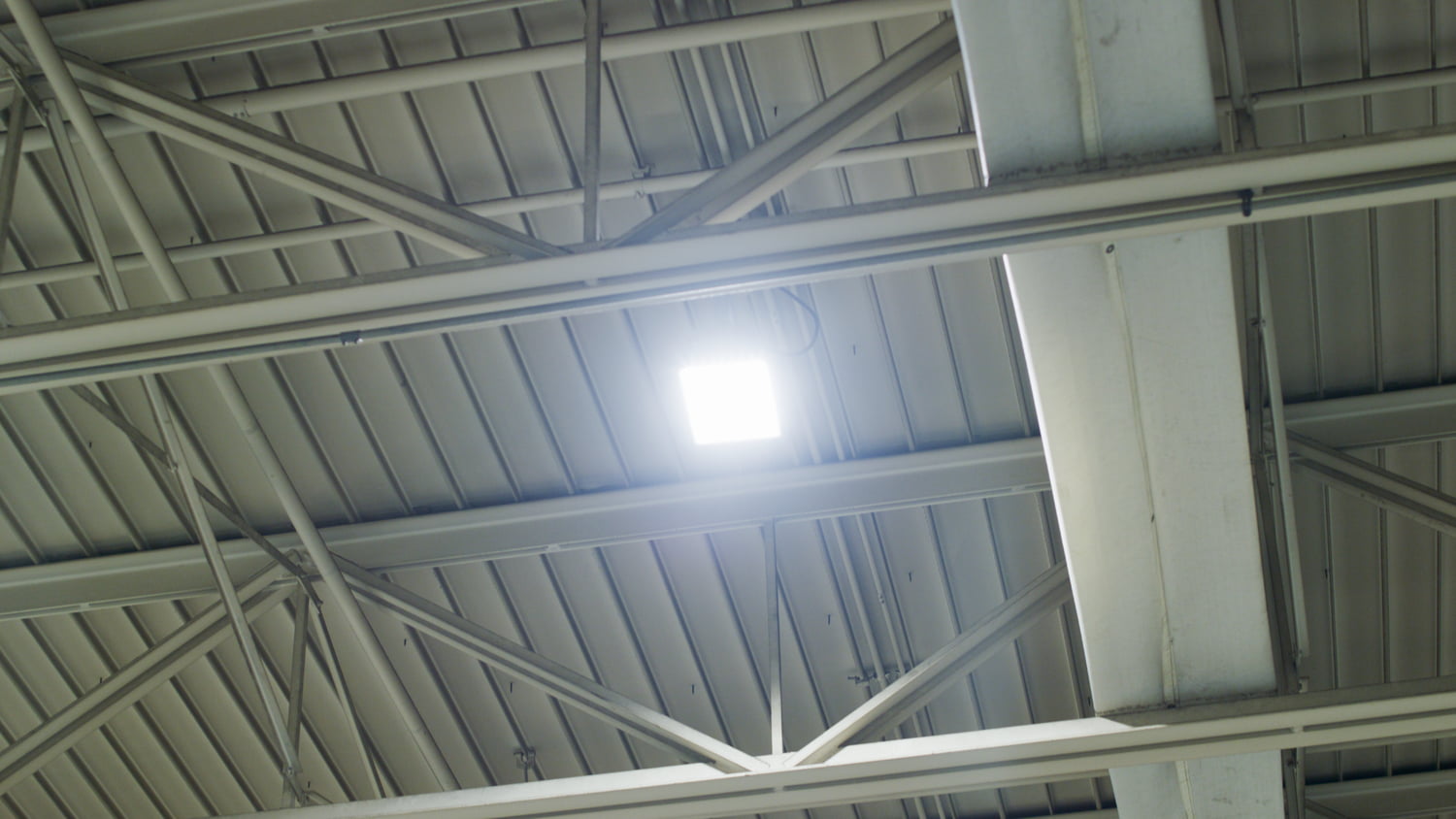 A square shaped explosion proof LED light mounted on the ceiling inside an industrial facility