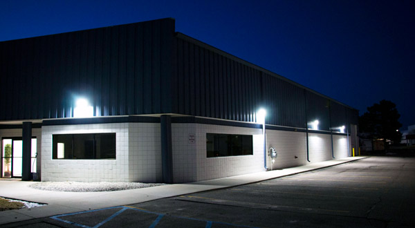 A building illuminating a parking lot at night with LED Wall Packs