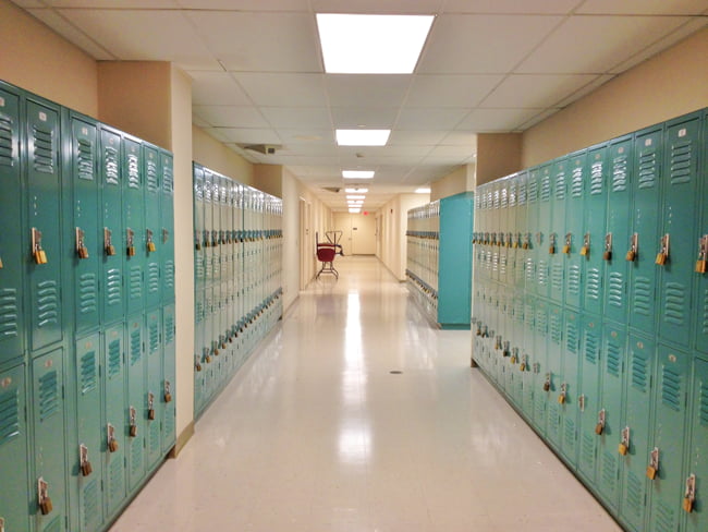 A school hallway with teal lockers illuminated by LED troffer lights above