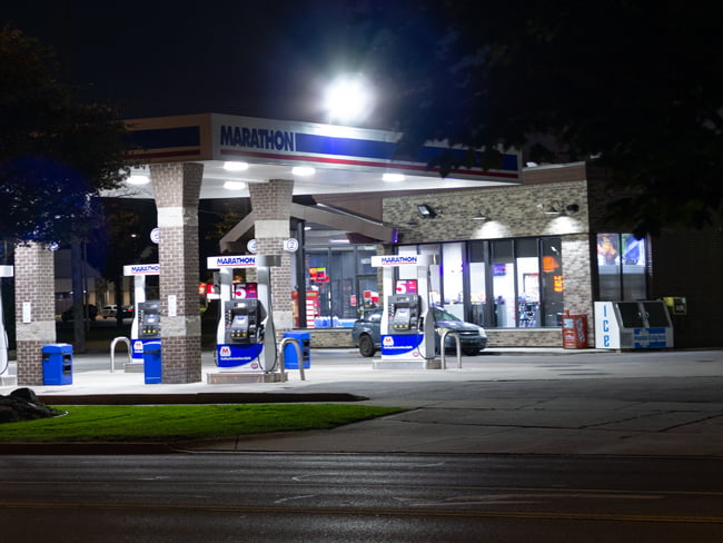 Gas station canopy with square shaped LED lights on the ceiling and a bright LED flood light on the roof providing illumination around the fuel pumps