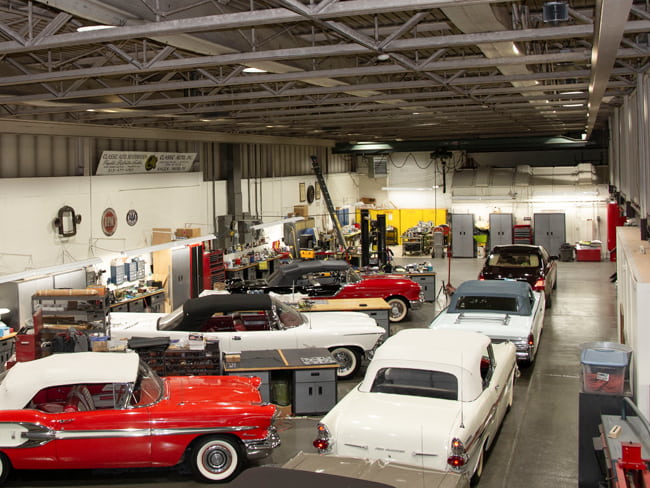 Round shaped UFO high bay lighting fixtures illuminating an automotive shop filled with classic cars