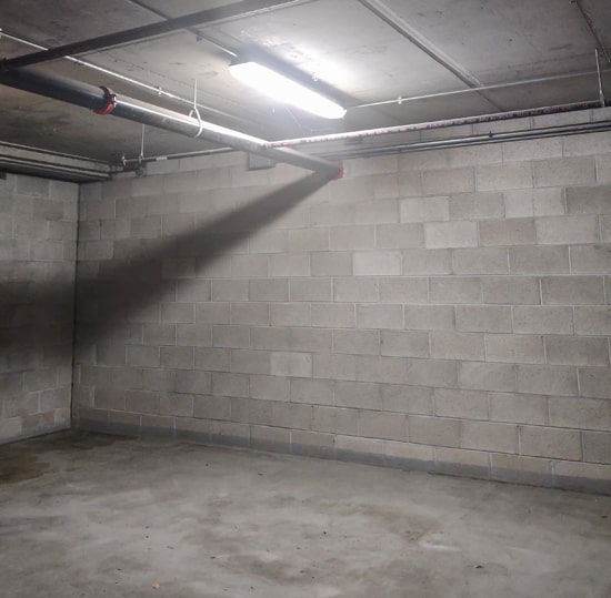 The basement of a parking garage is shown with vapor tight fixtures mounted on the concrete ceiling above