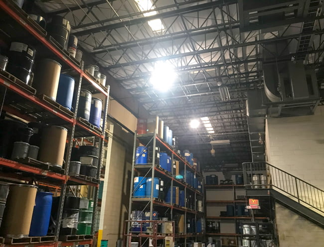 Square explosion proof LED high bay light on the ceiling of a paint storage warehouse casting bright illumination