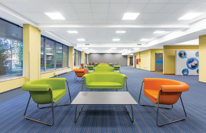 Large space inside a school being illuminated by LED flat panel lights from the ceiling